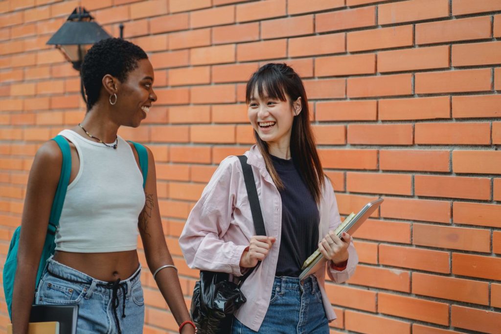 a couple of women standing next to a brick wall