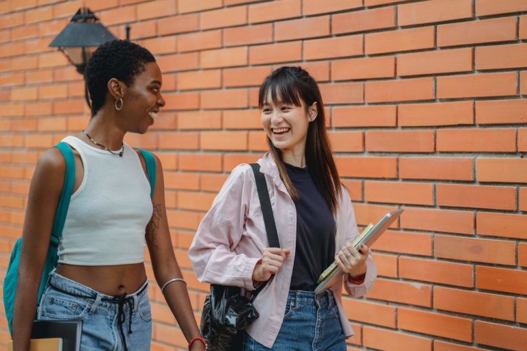 a couple of women standing next to a brick wall