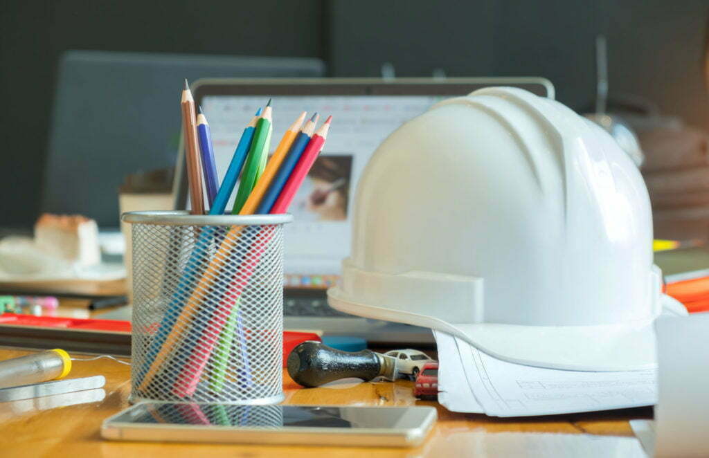a white mask on a table with a bunch of pencils and pens
