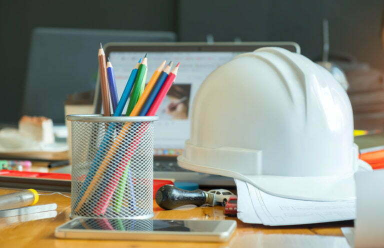 a white mask on a table with a bunch of pencils and pens