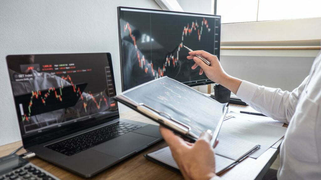 Stock exchange market concept, Business investor trading or stock brokers having a planning and analyzing with display screen and pointing on the data presented and deal on a stock exchange.