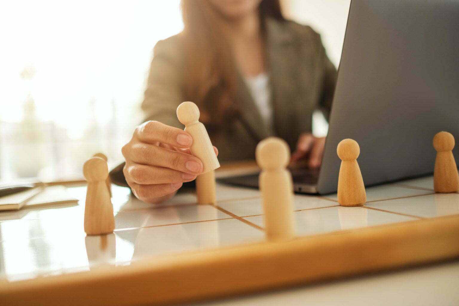 Businesswoman leader choosing wooden people from a group of employees on a planning board