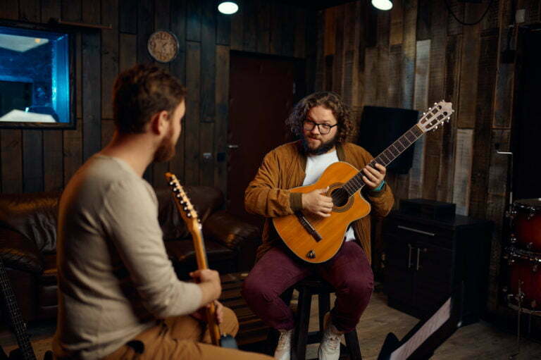 Music tutor explaining features of playing guitar